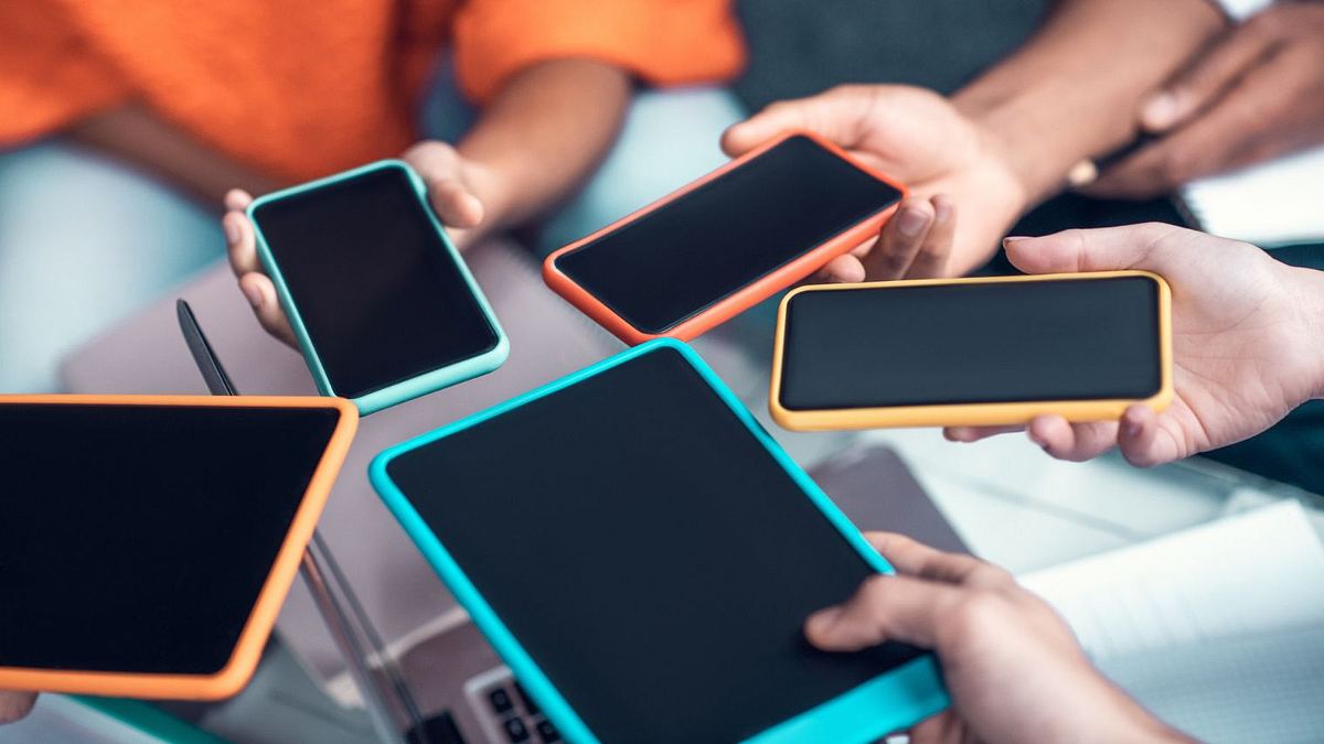 Smartphones Vergleich Verschiedene Smartphones werden in einem Kreis nebeneinander gehalten.