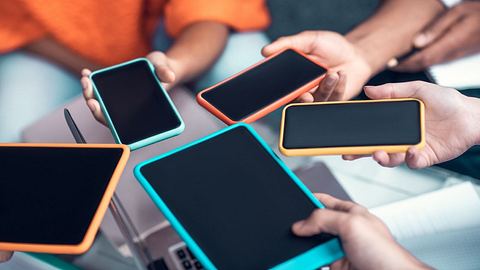 Verschiedene Smartphones werden in einem Kreis nebeneinander gehalten. - Foto: istock/Zinkevych