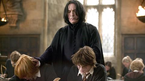 Severus Snape steht hinter Ron und Harry und drückt ihre Köpfe leicht nach vorne. - Foto: Warner Bros.