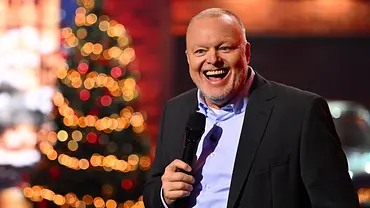 Stefan Raab moderiert lachend vor einem Weihnachtsbaum. - Foto: RTL / Raab Entertainment / Willi Weber