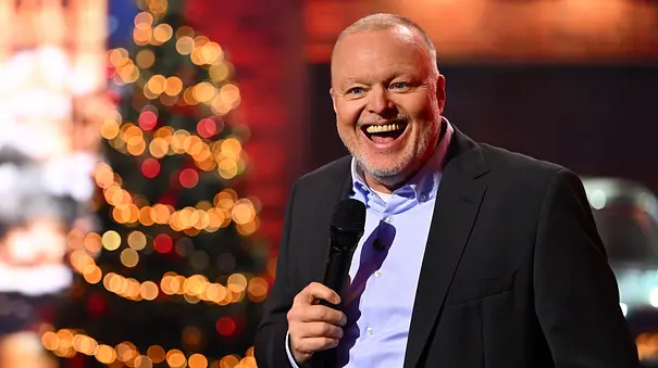 Stefan Raab moderiert lachend vor einem Weihnachtsbaum. - Foto: RTL / Raab Entertainment / Willi Weber
