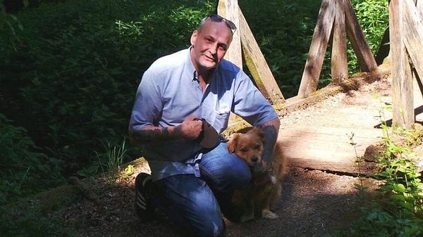 Ein privates Foto zeigt Dieter Wollny 2020 in blauem Hend neben seinem kleinen Mischlingshund knien - Foto: Privat (Nutzungsrechte exklusiv für TVMovie.de)
