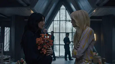 Camila Morrone (Rachel Harkin) und Gus Birney (Portia) in einem mit Licht durchfluteten Raum. Camilia hält Blumen und beide gucken sich angespannt an. - Foto: COURTESY OF NETFLIX