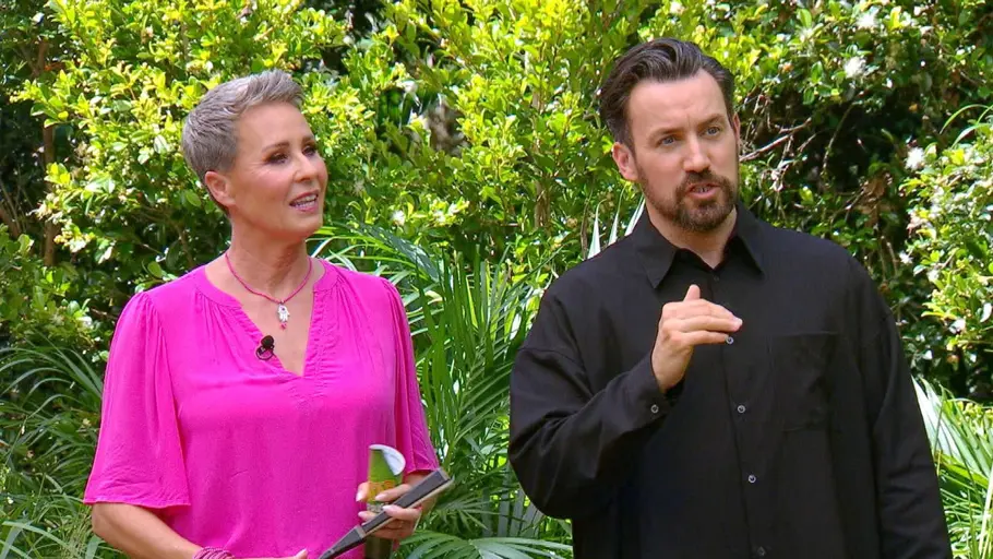 Sonja Zietlow trägt eine pinke Bluse und steht im Dschungel neben Jan Köppen.