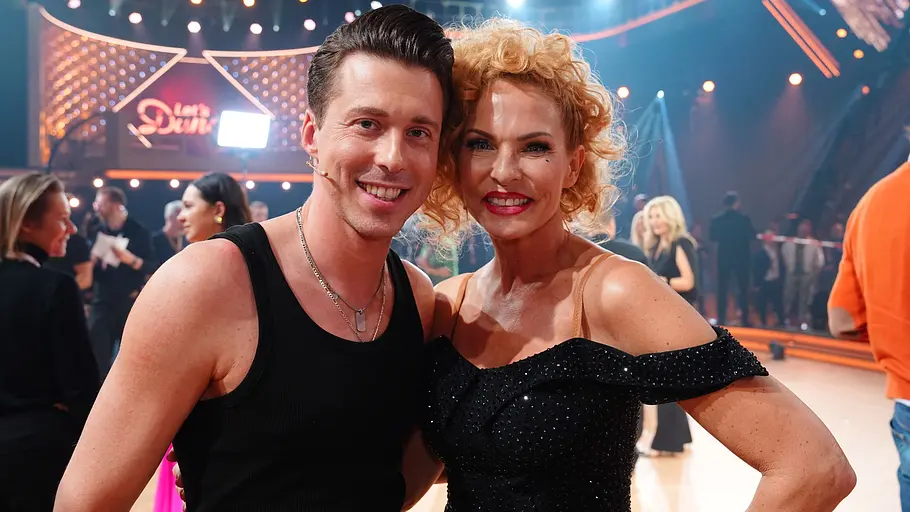 Sonya und Valentin Arm im Arm nach dem Show-Aus. Sie lächeln in die Kamera. Im Hintergrund laufen viele Leute druch die Show-Location.