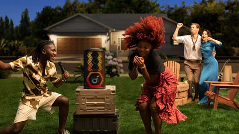 Zwei Personen tanzen vor einer Boom Box und haben Spaß, sie singen und Tanzen. Im Hintergrund ein tanzendes Paar - Foto: Soundcore/PR