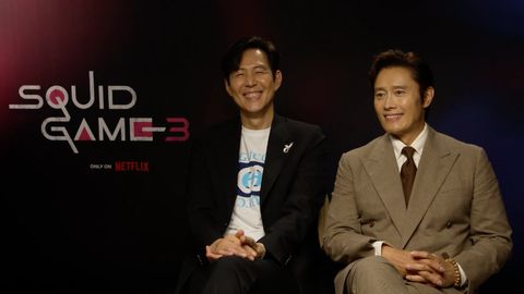 Lee Jung-Jae und Lee Byung-Hun sitzen vor einer Wand mit dem Squid Game Logo und lächeln - Foto: Netflix