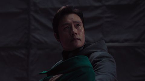 Lee Byun-hun hält in seiner Rolle als Frontmann ein Baby (Spielerin 222) im Arm und blickt in die Ferne - Foto: Netflix