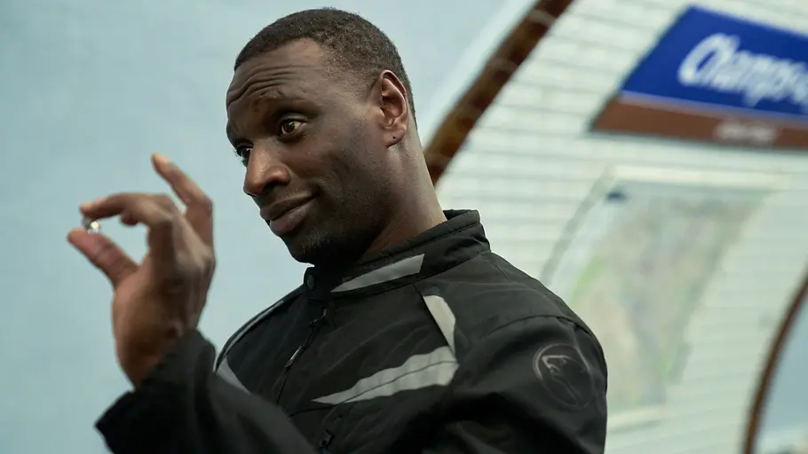 Staffel 4 könnte für Assane Diop gerade erst der Anfang gewesen sein. Assane Diop trägt eine schwarze Jacke und hält einen kleinen Diamanten zwischen Daumen und Zeigefinger.