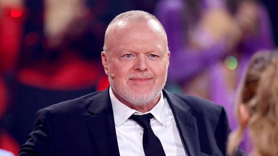 Stefan Raab sitzt im Anzug und lächelt leicht