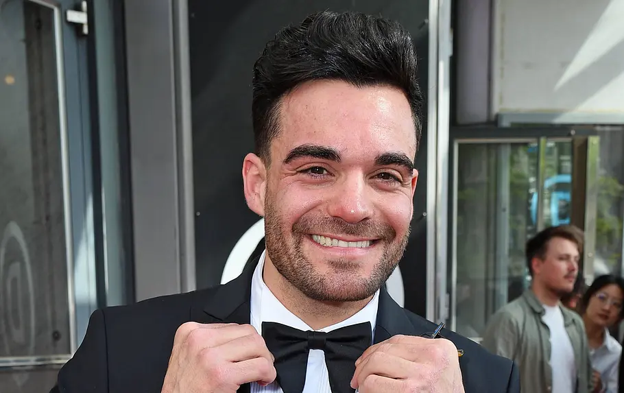  Stefano Zarrella grinst im Anzug samt Fliege in die Kamera. 
