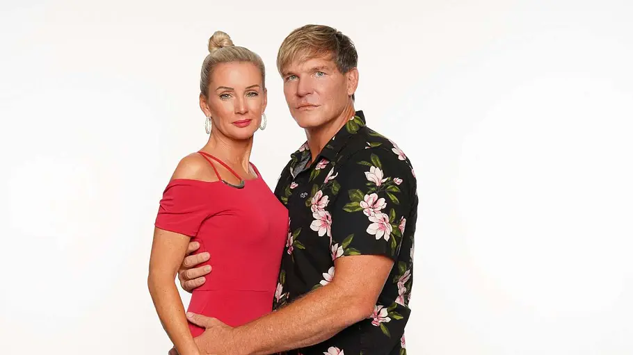 Steff Jerkel und Peggy Jerofke Peggy Jerofke im roten Kleid und Steff Jerkel im schwarzen Blumenhemd stehen eng umschlungen vor weißem Hintergrund.
