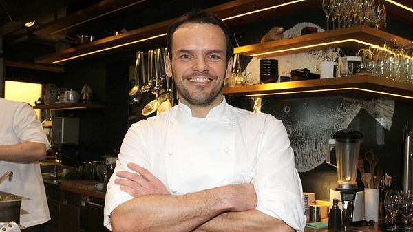 Steffen Henssler hat die Arme verschränkt und grinst in die Kamera - Foto: IMAGO / Eventpress