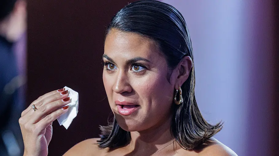 Steffi Brungs vor neutralem Hintergrund, während sie ein Taschentuch an ihr Gesicht führt.