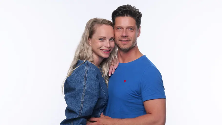 Stephen und Katharina Dürr Stephen und Katharina Dürr stehen eng umschlungen vor weißem Hintergrund. Sie trägt ein Jeanskleid, er ein blaues T-Shirt.