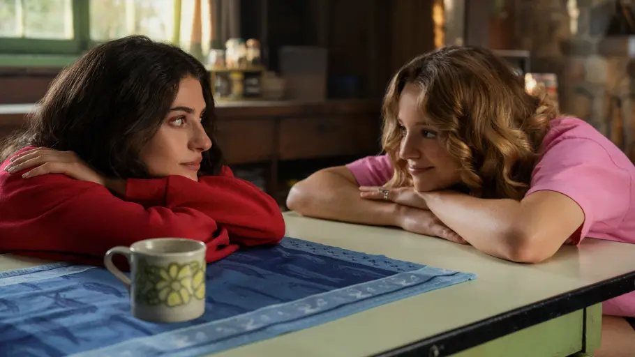 „Sterling Point“ Ramona und Annie lehnen über einem Tischt mit gekreuzten Armen und schauen einander an.