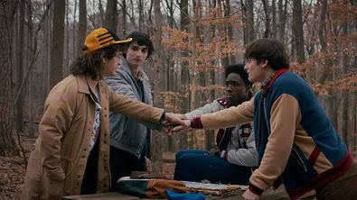 Dustin, Mike, Lucas und Will packen ihre Hände übereinander. - Foto: Courtesy of Netflix