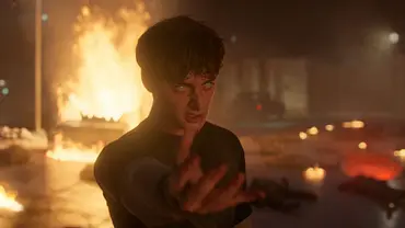 Will steht vor einer brennenden Kulisse, seine Augen sind komplett weiß und er hebt seine Hand nach vorne. - Foto: COURTESY OF NETFLIX