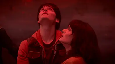 Will und Joyce stehen in einem rot umleuchtenden Raum und schauen nach oben. - Foto: Netflix