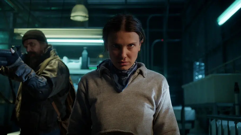 Eleven in Stranger Things Staffel 5 Eleven steht in einem Labor und schaut ernst Richtung Kamera. Ihre Nase blutet.