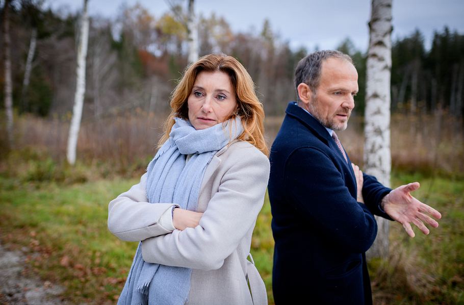 Alexandra und Markus stehen in der Natur fast Rücken und an Rücken und diskutieren.