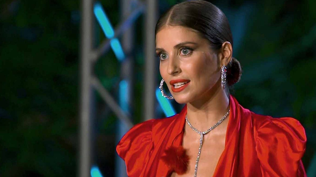 Cathy Hummels spielt bei Sturm der Liebe mit Cathy Hummels trägt ein rotes Kleid und schaut fassungslos in die Ferne