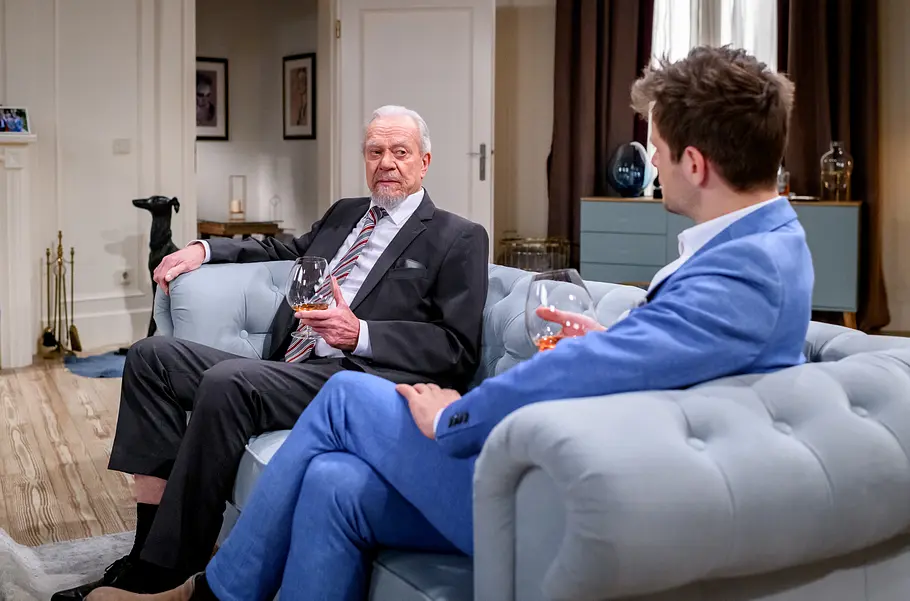 Sturm der Liebe-Vorschau: Dirk Galuba und Philip Birnstil sitzen in einer neuen Sturm der Liebe-Folge in dunklem und blauem Anzug mit gefüllten Schwenkgläsern auf einem hellblauen Sofa.