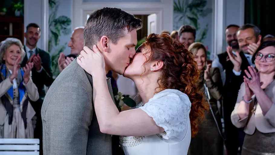STURM DER LIEBE-Vorschau FOLGE 4660 Dienstag 27. Oktober STURM DER LIEBE-Vorschau FOLGE 4660, Dienstag (27.10.2026): Fanny (Johanna Graen r.) und Marlon (Frederik Bott l.) küssen sich vorm Traualtar, Freunde und Kollegen klatschen beim Kuss begeistert.