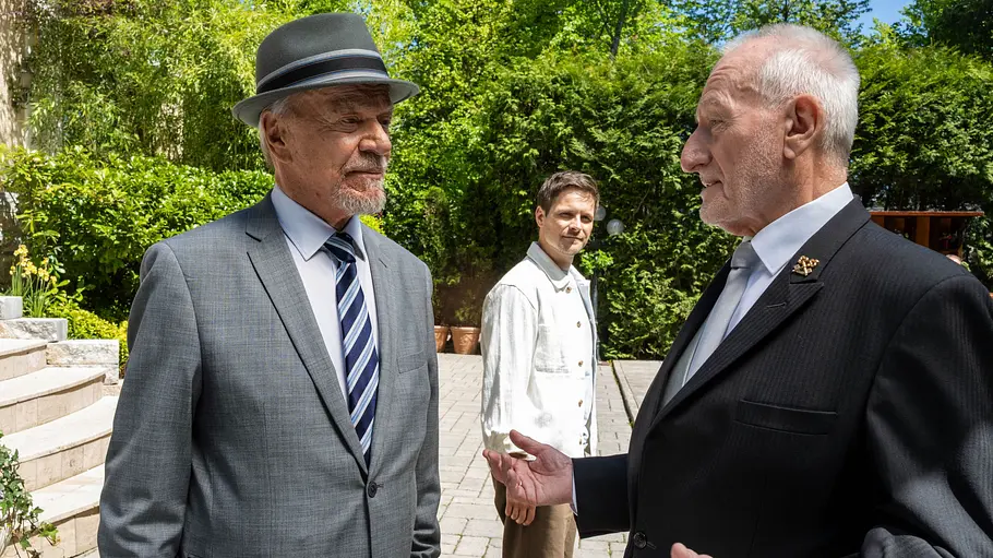 Werner und Alfons diskutieren vor dem Fürstenhof. Im Hintergrund ist Massimo zu sehen