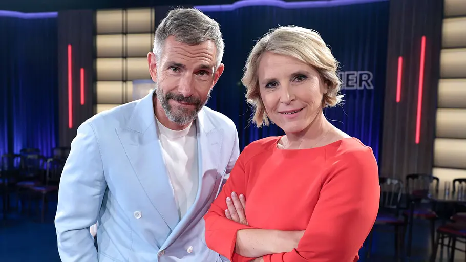 Susan Link und Micky Beisenherz Moderatorin Susan Link und Moderator Micky Beisenherz stehen gemeinsam in einem TV-Studio und blicken lächelnd in die Kamera.