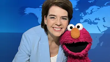 Susanne Daubner sitzt im „Tagesschau“-Studio neben Elmo und lächelt in die Kamera. - Foto: NDR / Wibke Harms