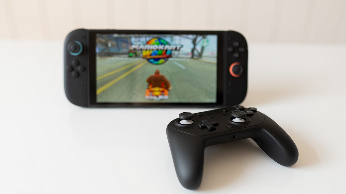 Switch 2 Pro Controller passt zur Nintendo Konsole Der Switch 2 Pro Controller liegt vor der Switch-2-Konsole auf cremefarbenden Hintergrund. Mario Kart World läuft auf der Switch 2.