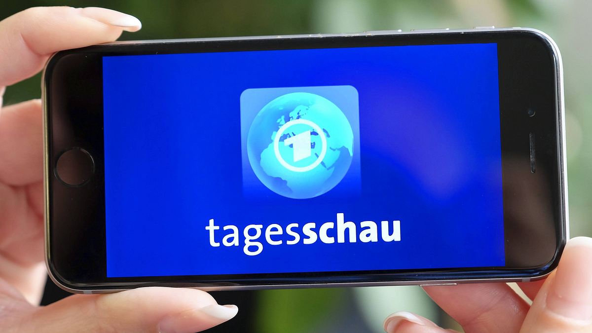 Tagesschau-XXL Person hält in Handy in beiden Händen und sieht darauf das Logo der Tagesschau.