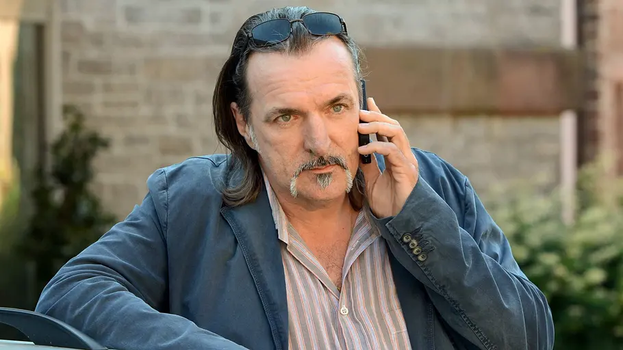 Mario Kopper telefoniert während er an ein Auto lehnt. 