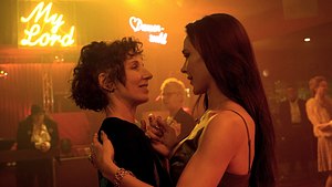 Meret Becker (links) und Bella Dayne tanzen in Abendkleidung in einer Lesbenbar. Das Licht ist orange. - Foto: rbb/Aki Pfeiffer
