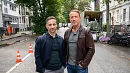 Denis Moschitto und Wotan Wilke Möhring stehen auf einer Hamburger Straße und schauen zufrieden in die Kamera. - Foto: NDR/Georges Pauly Denis Moschitto und Wotan Wilke Möhring stehen auf einer Hamburger Straße und schauen zufrieden in die Kamera. - Foto: NDR/Georges Pauly