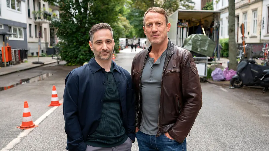 Tatort: Paranoia Denis Moschitto und Wotan Wilke Möhring stehen auf einer Hamburger Straße und schauen zufrieden in die Kamera.