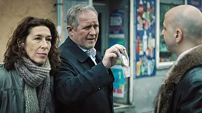 Fellner (l.) und Eisner (r.) halten einem glatzköpfigen Mann ihren Dienstausweis vor. - Foto: WDR/ARD Degeto/ORF