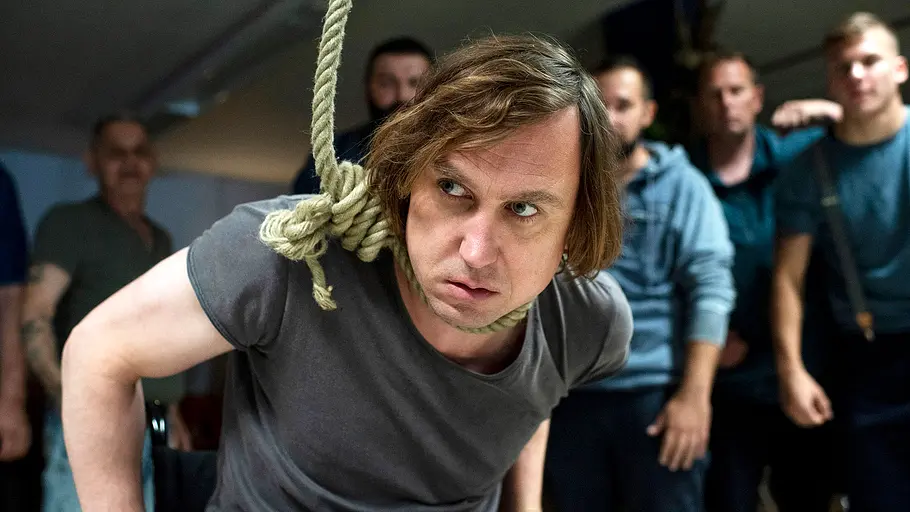 Tatort - Borowski und der gute Mensch Lars Eidinger hat eine Schlinge um den Hals und ist von etlichen Personen umringt.