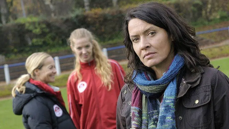 Tatort: Im Abseits Odenthal steht neben zwei Fußballspielerinnen auf einem Fußballplatz.