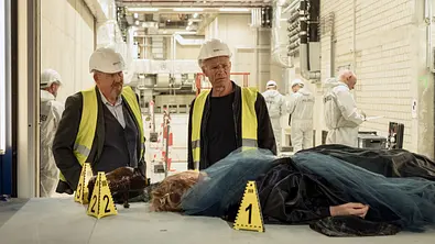 Dietmär Bär (l.) und Klaus J. Behrendt stehen in Schutzkleidung vor einer Leiche. - Foto: WDR/Thomas Kost