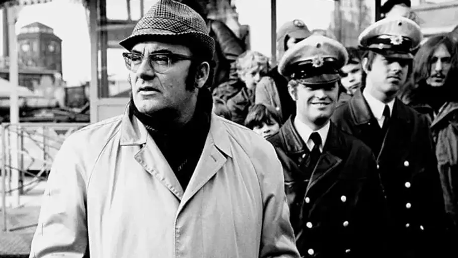 Tatort Ermittler Böck steht im Mantel und Hur vor zwei Polizisten.