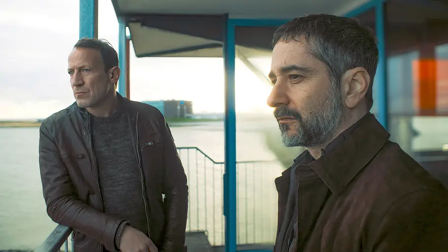 Wotan Wilke Möhring (l.) und Denis Moschitto stehen an einem Geländer und schauen in die Ferne.
