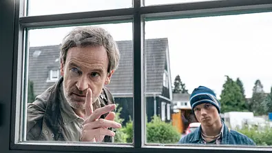  Faber (Jörg Hartmann) und Finn Gebken (Caspar Hoffman, r) schauen durch ein Fenster.  - Foto: WDR/Martin Rottenkolber