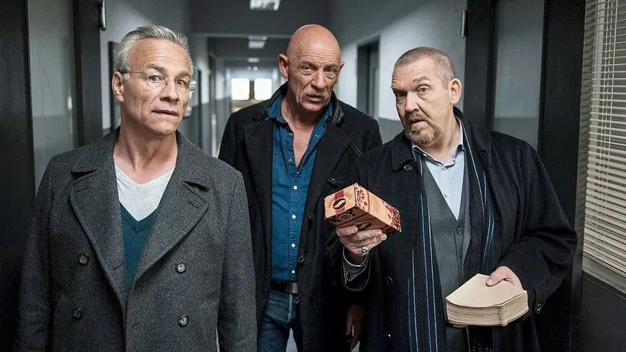 Tatort: Freddy tanzt Ballauf, Roth und Schenk schauen in die Kamera. Schenk hält Kaffee und dazugehörige Filter.