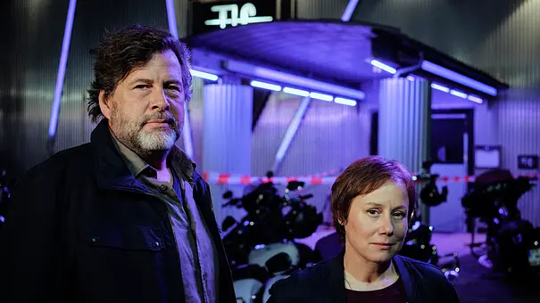 Hans-Jochen Wagner und Eva Löbau stehen vor einem Club. - Foto: SWR/Benoît Linder Hans-Jochen Wagner und Eva Löbau stehen vor einem Club. - Foto: SWR/Benoît Linder
