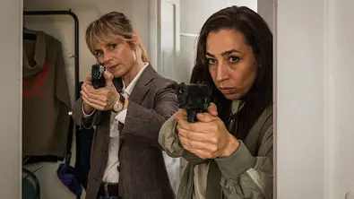 Anna Pieri Zuercher und Carol Schuler stehen für den „Tatort“ in einer Wohnung und zielen mit ihren Waffen.  - Foto: SRF/Sava Hlavacek