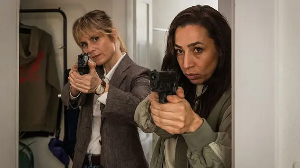 Anna Pieri Zuercher und Carol Schuler stehen für den „Tatort“ in einer Wohnung und zielen mit ihren Waffen. - Foto: SRF/Sava Hlavacek Anna Pieri Zuercher und Carol Schuler stehen für den „Tatort“ in einer Wohnung und zielen mit ihren Waffen. - Foto: SRF/Sava Hlavacek