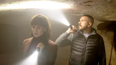 Melika Foroutan (links) und Edin Hasanovic durchleuchten einen dunklen Gang mit hellen Taschenlampen. - Foto: HR/Sommerhaus/Tatiana Vdovenko