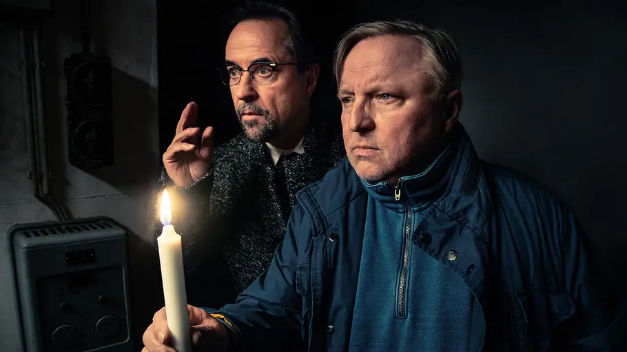 Tatort - Man stirbt nur zweimal Jan Josef Liefers und Axel Prahl stehen im spärlichen Kerzenschein in der Dunkelheit.
